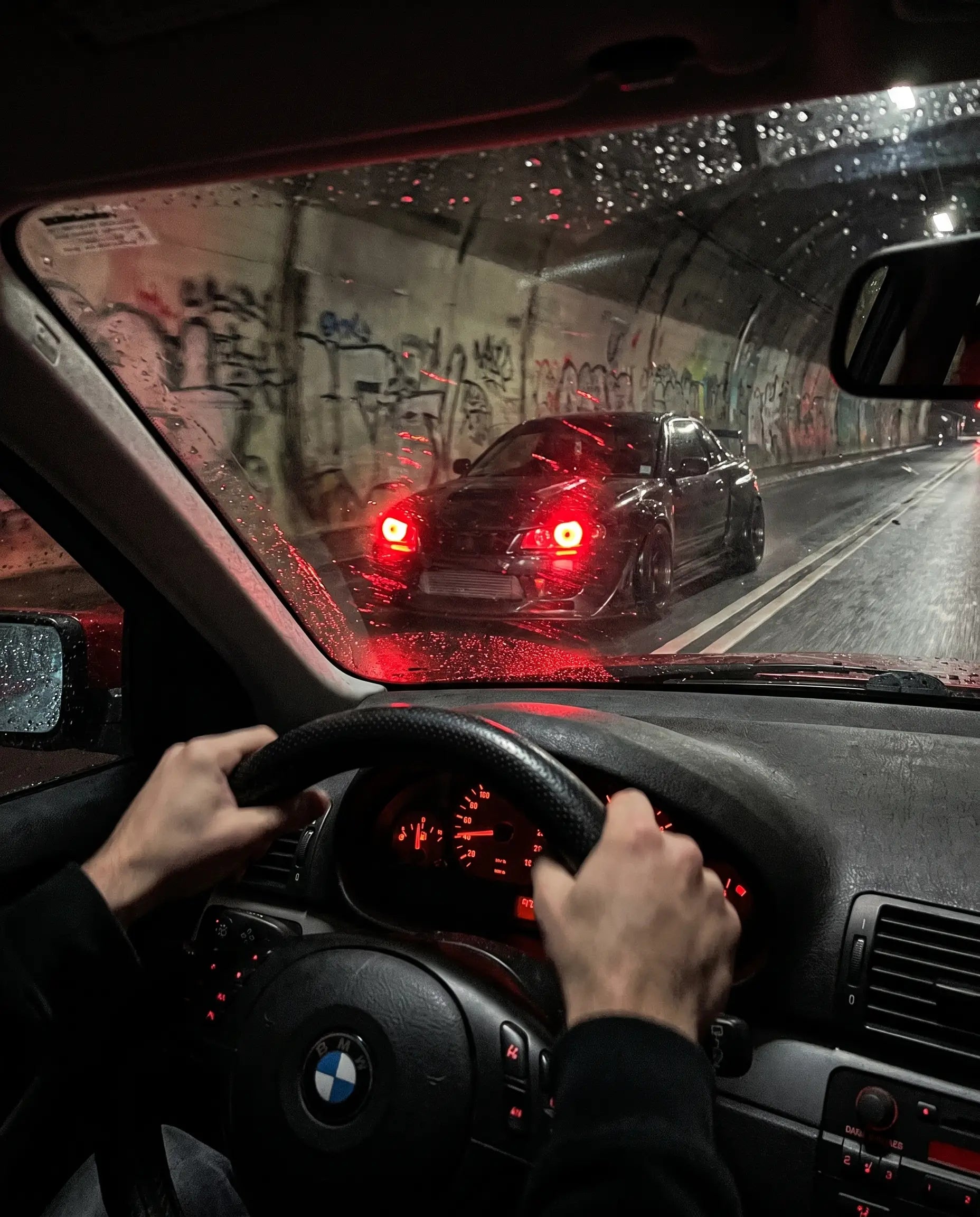 POV driving shot through a night tunnel with another car's Nyxora Demon-Eye LED headlights glowing red